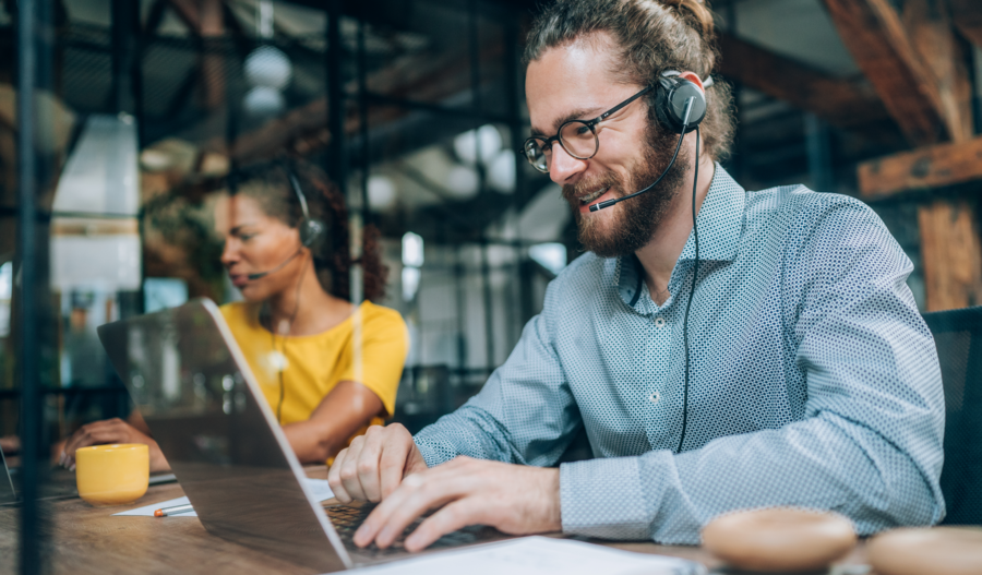 Guy smiling when working as support via a computer.