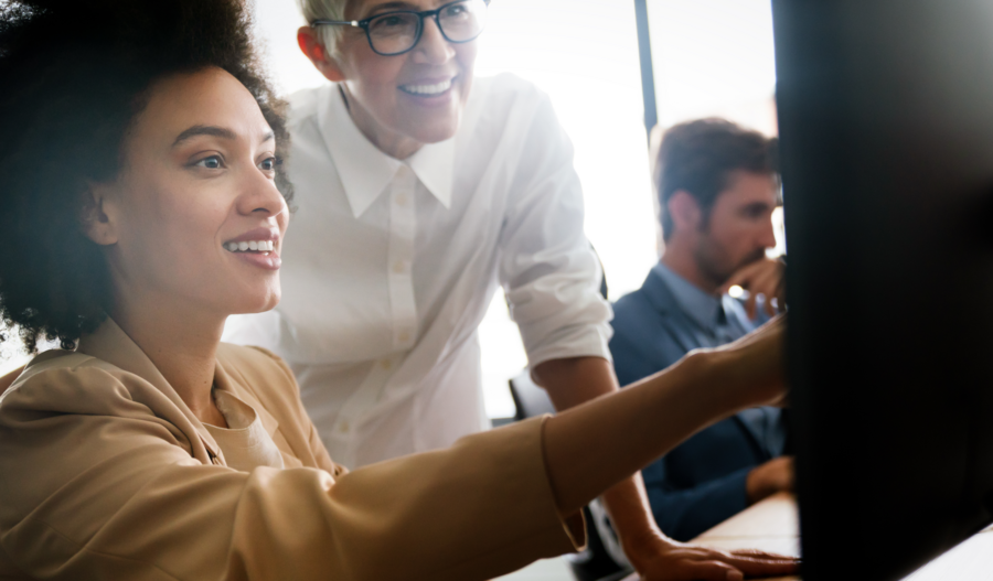 A woman smiling and pointing towards a screen.
