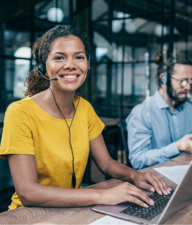 A woman smiling and pointing towards a screen.